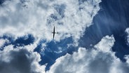 Blick von unten auf ein Flugzeug an blauem Himmel mit Wolken. © NDR Foto: Dirk Wenzel