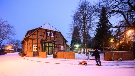 Ein Mann fegt mit einer Maschine Schnee vor einem Fachwerkhaus in Laatzen. © dpa-Bildfunk Foto: Julian Stratenschulte