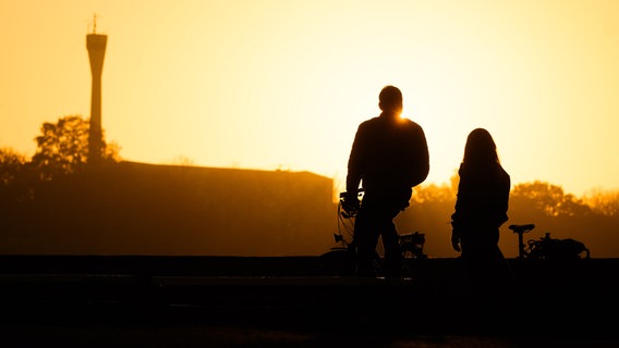 Ein Paar steht bei Sonnenaufgang am Ufer vom Maschsee. © dpa-Bildfunk Foto: Julian Stratenschulte/dpa