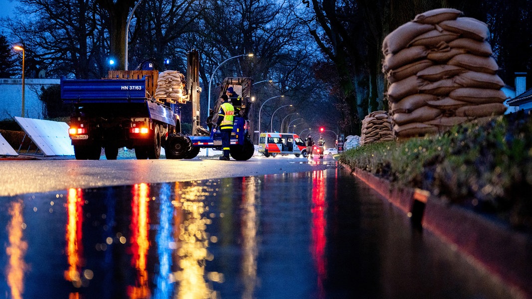 Einsatzkräfte des Technischen Hilfswerks laden bei Regen zahlreiche Sandsäcke an der Sandkruger Straße im Stadtteil Bümmerstede in Oldenburg ab.