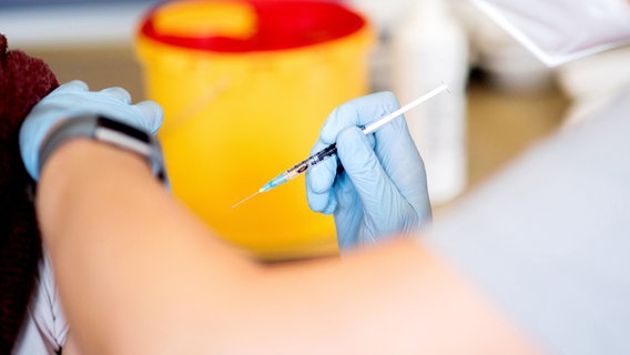 Eine Impfspritze wird in Richtung eines freigemachten Arms gehalten. © dpa-Bildfunk Foto: Hauke-Christian Dittrich