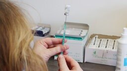 Eine Frau zieht in einer Hausarztpraxis eine Spritze mit dem Corona-Impfstoff von Biontech/Pfizer auf.