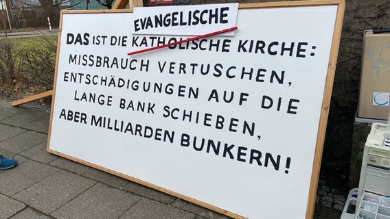 Im Vorfeld der Vorstellung einer Studie zu sexualisierter Gewalt in der evangelischen Kirche stellen Demonstrierende ein Plakat auf. © NDR Foto: Christina Harland