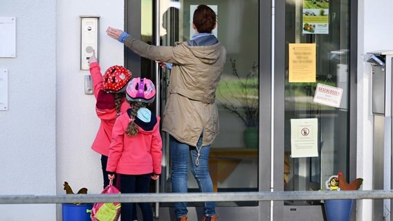 A mother rings the doorbell with two children.  © picture alliance / dpa Photo: Uwe Zucchi