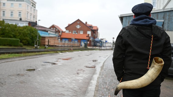 Ein Borkumer zieht mit einem Kuhhorn auf dem Rücken über die Insel. © dpa-Bildfunk Foto: Lars Penning