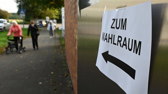 Ein Zettel mit der Aufschrift "Zum Wahlraum" hängt an einem Wahllokal. © dpa Foto: Swen Pförtner