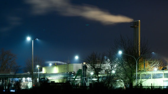 Ein industrieller Schornstein stößt in Göttingen eine weiße Wolke in den dunklen Nachthimmel aus. © picture alliance Foto: Swen Pförtner