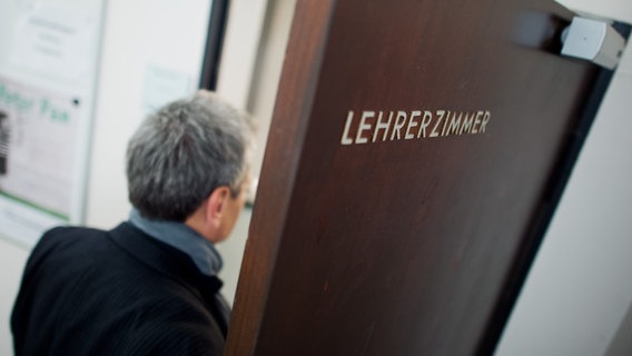 Ein Mann geht durch eine Tür auf der "Lehrerzimmer" steht. © picture alliance / dpa Foto: Julian Stratenschulte