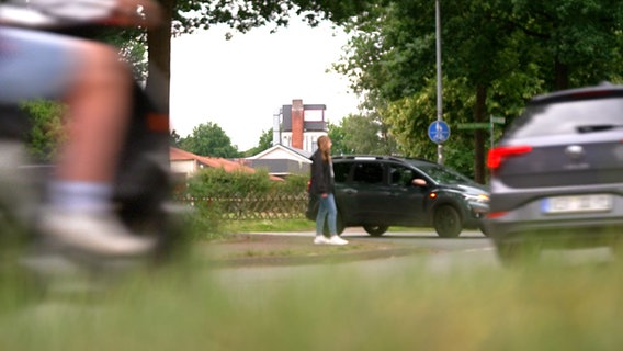 Eine Frau steht an einer viel befahreren Straße. © NDR 