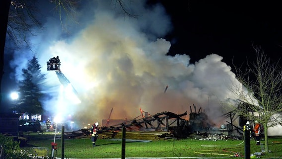 Feuerwehrleute löschen unter Einsatz einer Drehleiter nachts eine brennende Scheune in Asendorf. © Nord-West-Media TV 