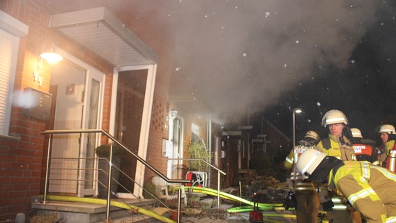 Feuerwehrkräfte stehen vor einem Reihenhaus, aus dem Rauch kommt. © Feuerwehr Stade 