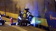 Feuerwehrleute knien auf einem Bahnsteig vor einem qualmenden Zug. © TV-Elbnews 