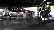 Feuerwehrleute löschen ein brennendes Auto in einem Parkhaus in Buchholz. © Hellwig TV Elbnews Produktion 