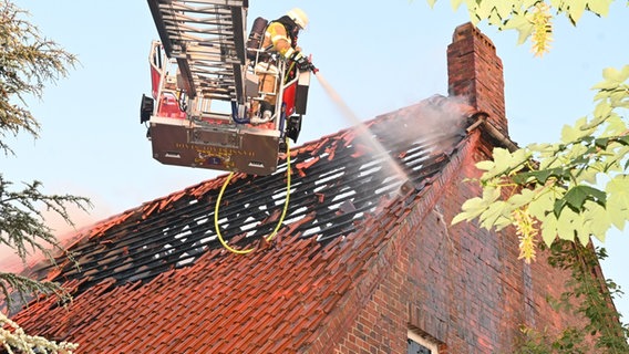 Feuerwehrmann löscht ein Dach von einer Drehleiter aus © Polizeiinspektion Stade 