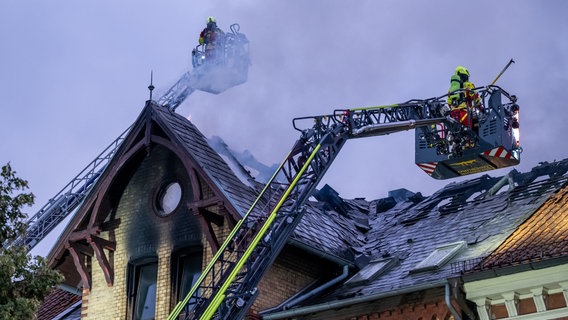 Feuerwehrleute löschen von einer Drehleiter aus einen Dachstuhlbrand in Lüneburg. © dpa Bildfunk Foto: Philipp Schulze