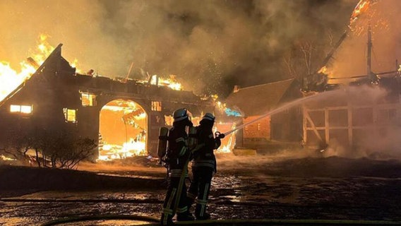 Feuerwehrleute löschen brennende Reetdachhäuser in Dollern. © Polizei Stade 