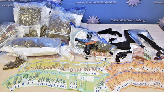 Drogen, Waffen und Geld liegen nach einer Beschlagnahmung auf einem Tisch der Polizei. © Polizeiinspektion Harburg 