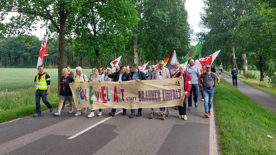 Menschen mit Fahnen und Banner laufen bei einer Demo gegen Rechtsextremismus über eine Straße im Landkreis Celle. © NDR Foto: Julia Scheper