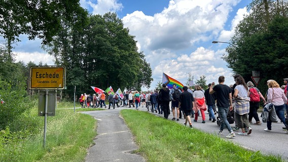 Menschen mit Fahnen und Banner laufen bei einer Demo gegen Rechtsextremismus über eine Straße in Eschede im Landkreis Celle. © NDR Foto: Marie Schiller