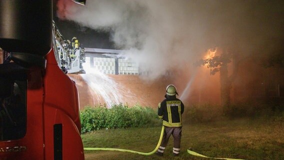 Feuerwehrleute löschen eine Gebäude aus dem Flammen schlagen. © Kreisfeuerwehr Lüchow-Dannenberg Foto: Florian Schulz