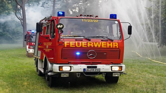 Ein Löschfahrzeug der Feuerwehr steht auf einer Rasenfläche, Sprinkler daneben versprühen Wasser. © Ordnungsamt Stadt Bleckede 