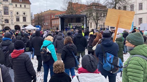 Menschen stehen in Lüneburg auf einem Platz und schauen in Richtung einer Bühne © NDR Foto: Mikala Tinius