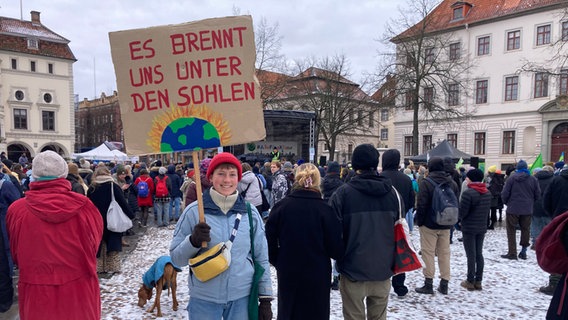 Eine junge Frau steht mit einem Schild auf einer Demonstration in Lüneburg. © NDR Foto: Mikala Tinius