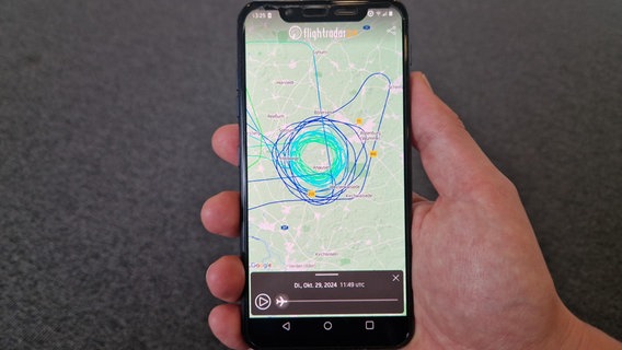 Auf einem Handy ist eine Landkarte zu sehen, auf der mit Linien die kreisende Flugbewegung eines Flugzeugs nachzuvollziehen ist. © NDR Foto: Janina Possel
