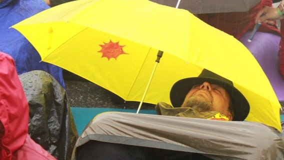 Ein Atomkraft-Gegner schläft unter seinem Regenschirm auf der Straße.  Foto: Harald Ganswindt