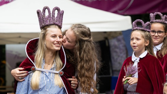 Die 24-jährige Nele Rörup  bekommt nach ihrer Wahl zur neuen Heidekönigin von ihrer Vorgängerin Lisa Röttger ein Küsschen. © picture alliance / dpa Foto: Philipp Schulze