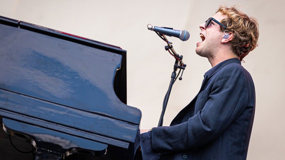 Der britische Singer-Songwriter und Pianist Tom Odell sitzt beim Hurricane Festival am Piano und singt. © dpa Foto: Moritz Frankenberg