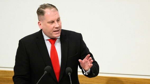 Der AfD-Landtagsabgeordnete Peer Lilienthal steht hinter einem braunen Rednerpult im Landtag in Niedersachsen. © Philip Dulian/dpa Foto: Philip Dulian