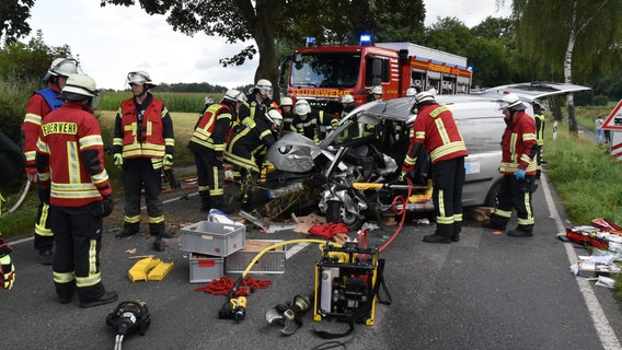 Feuerwehrleute stehen auf der Kreisstraße 5 vor einem schwer beschädigten Unfall-Auto. © Freiwillige Feuerwehr Landkreis Harburg 