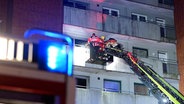 Feuerwehrleute bei einem Einsatz auf einer Drehleiter an einem Mehrfamilienhaus in Lüneburg, das nach einem Kellerbrand evakuiert werden muss. © TeleNewsNetwork 