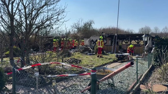 Einsatzkräfte der Feuerwehr stehen in einem Kleingarten. © TeleNewsNetwork 