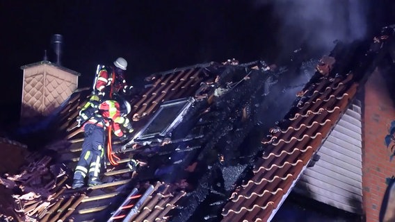 Feuerwehrleute stehen auf dem Dach eines brennenden Hauses. © Hellwig TV Elbnews Produktion 
