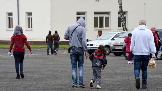 Mehrere Kinder und Erwachsene gehen über das Gelände der Notunterkunft. © dpa-Bildfunk Foto: Holger Hollemann