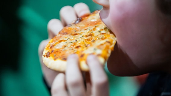 Ein Kind beißt in ein Stück Pizza. © picture alliance/dpa | Christoph Soeder Foto: Christoph Soeder