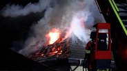 Feuerwehrleute stehen vor einem brennenden Einfamilienhaus in Rotenburg. © TV Elbnews 