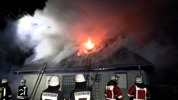 Feuerwehrleute stehen vor einem brennenden Einfamilienhaus in Rotenburg. © TV Elbnews 