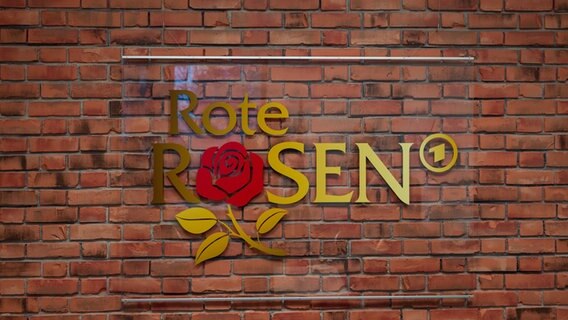 Das Logo der Telenovela "Rote Rosen" ist auf einer Backsteinmauer zu sehen. © dpa - Bildfunk Foto: Philipp Schulze