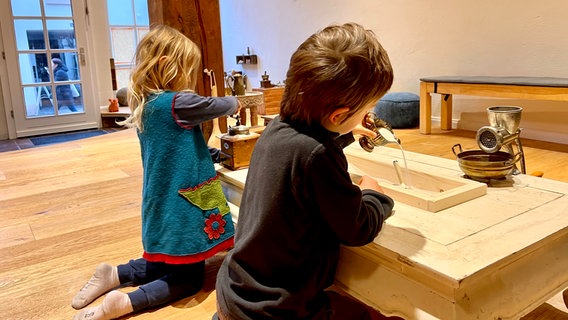 Zwei Kinder spielen mit alten Küchenutensilien in einem Sandkasten. © Maximilian Suermann 