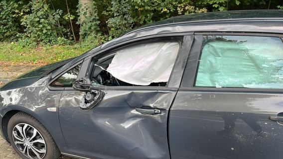 Ein dunkelblaues Auto mit Schäden an der Fahrerseite und einem kaputten Fenster. © Polizei Horneburg 