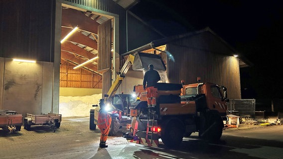 Mitarbeiter des Winterdienstes stehen in Lüneburg vor einem Lager mit Streusalz. © NDR Foto: Marie Schiller