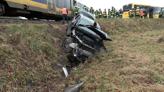 Ein Auto liegt nach einem Zusammenstoß mit einem Zug neben dem Bahnwall. © NonstopNews 