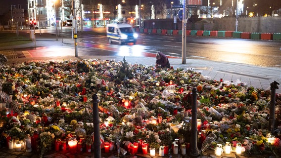 Zahlreiche Kerzen, Blumen und Kränze liegen beziehungsweise stehen vor dem Eingang der Johanniskirche in Magdeburg. © dpa-Bildfunk Foto: Sebastian Kahnert