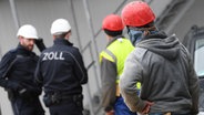 Beamte des Zoll kontrollieren Bauarbeiter während eines Einsatzes auf einer Großbaustelle. © picture alliance/dpa Foto: Arne Dedert