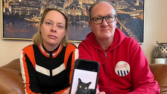 Catharina Majert und ihr Mann Gunnar zeigen auf einem Smartphone ein Foto ihrer Bombay-Katze Aramis. © dpa-bildfunk Foto: Volker Bartels