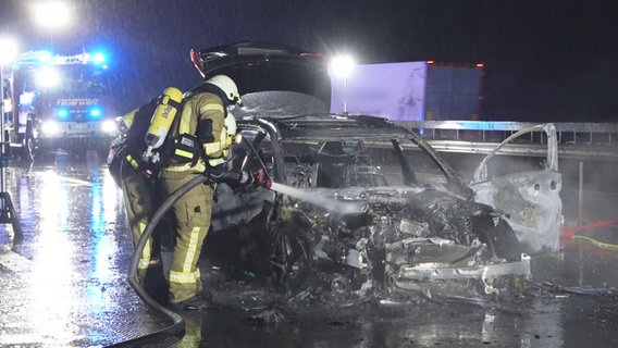 Feuerwehrleute an einem ausgebrannten Auto nach einem Unfall auf der A1 bei Cappeln. © NonstopNews 