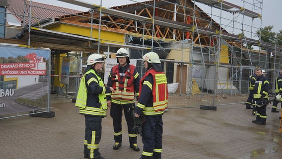 Einsatzkräfte der Feuerwehr stehen vor einem Netto Supermarkt bei dem nach starken Regenfällen das Dach nachgegeben hat. © Nord-West-Media TV 